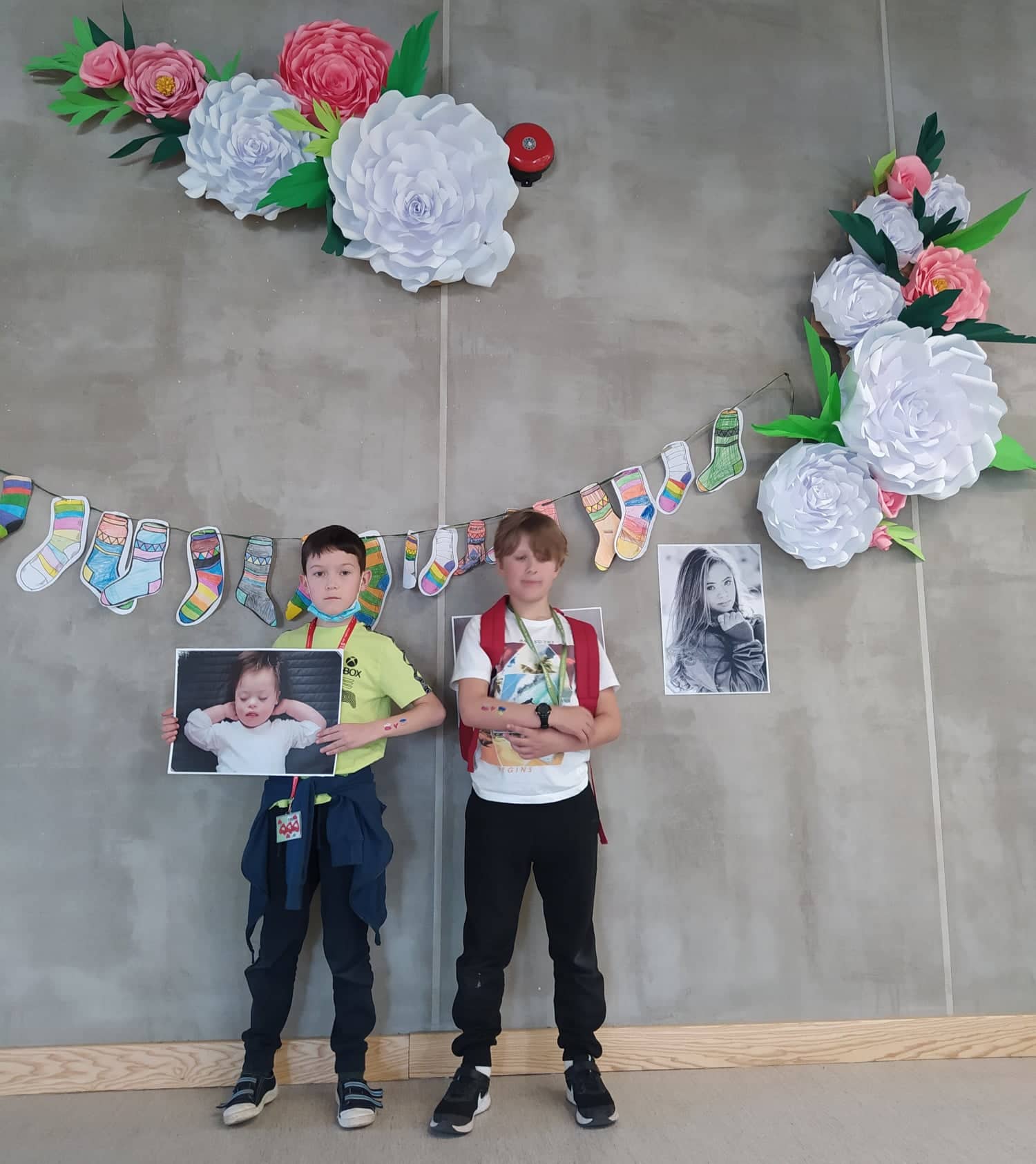 dwóch uczniów stoi pod ścianą na której zawieszone są rysowane skarpety